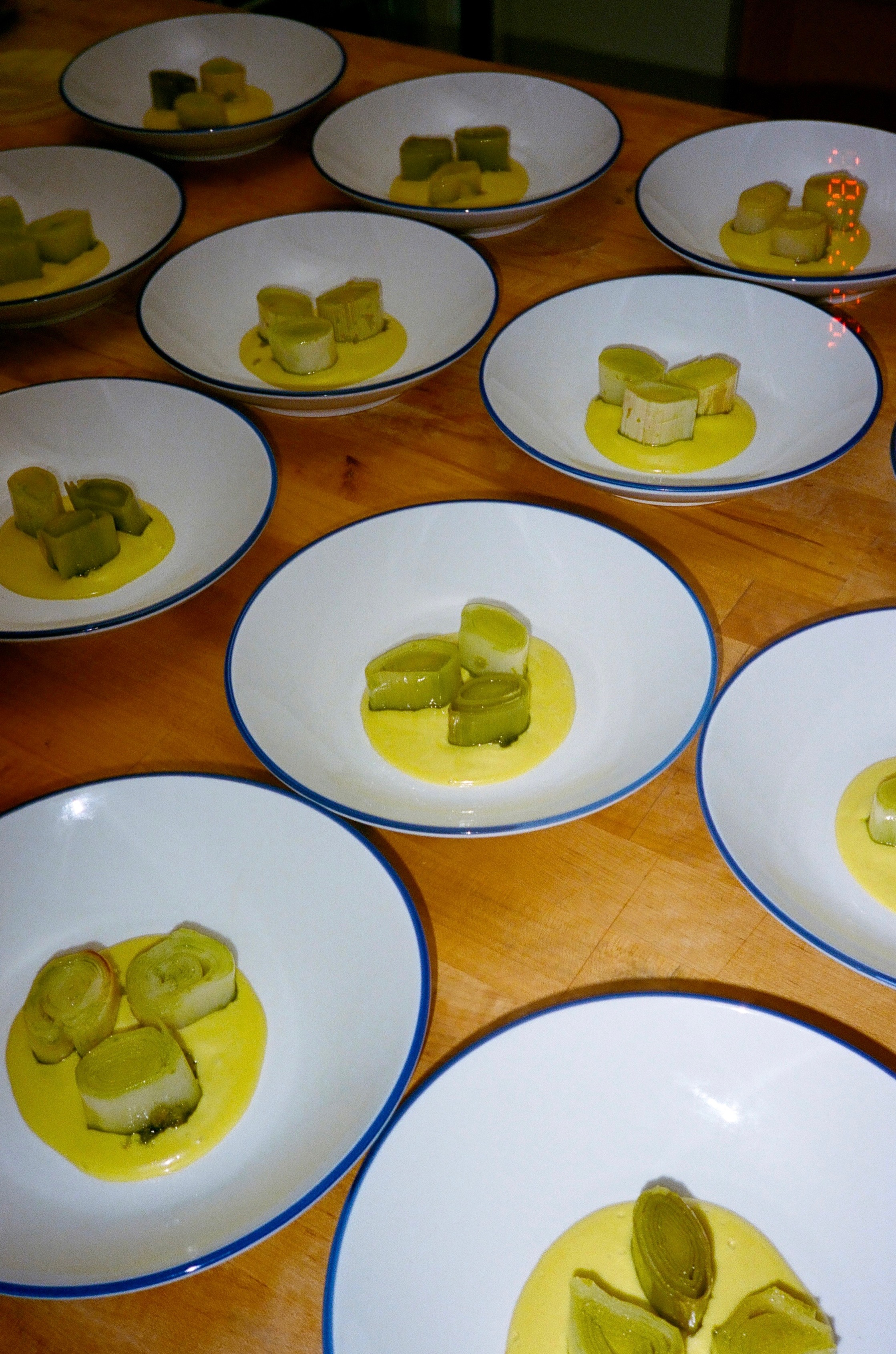 Beautifully plated leeks in yellow sauce served in white and blue-rimmed bowls