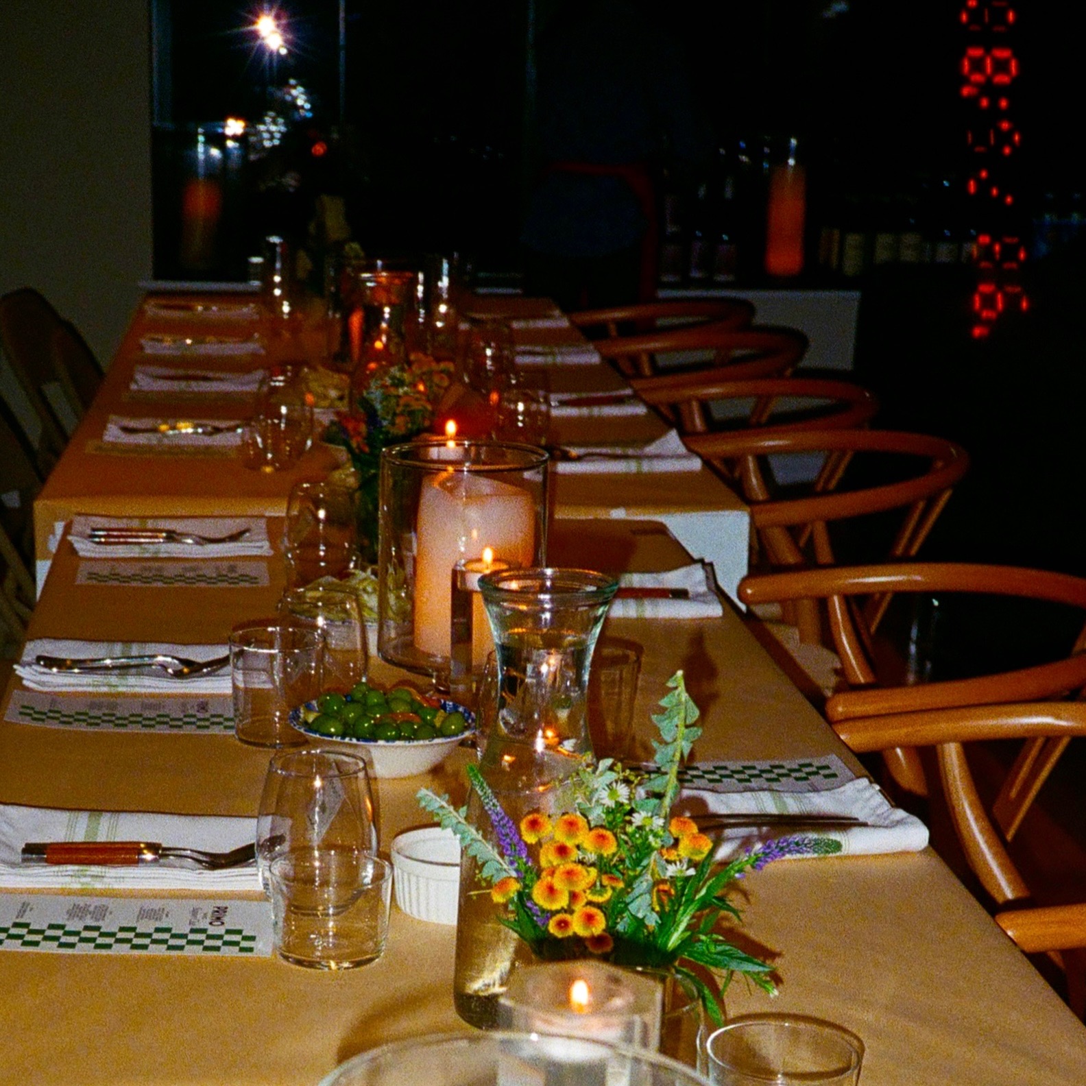 Long dinner table setup with multiple place settings, candles, and floral arrangements