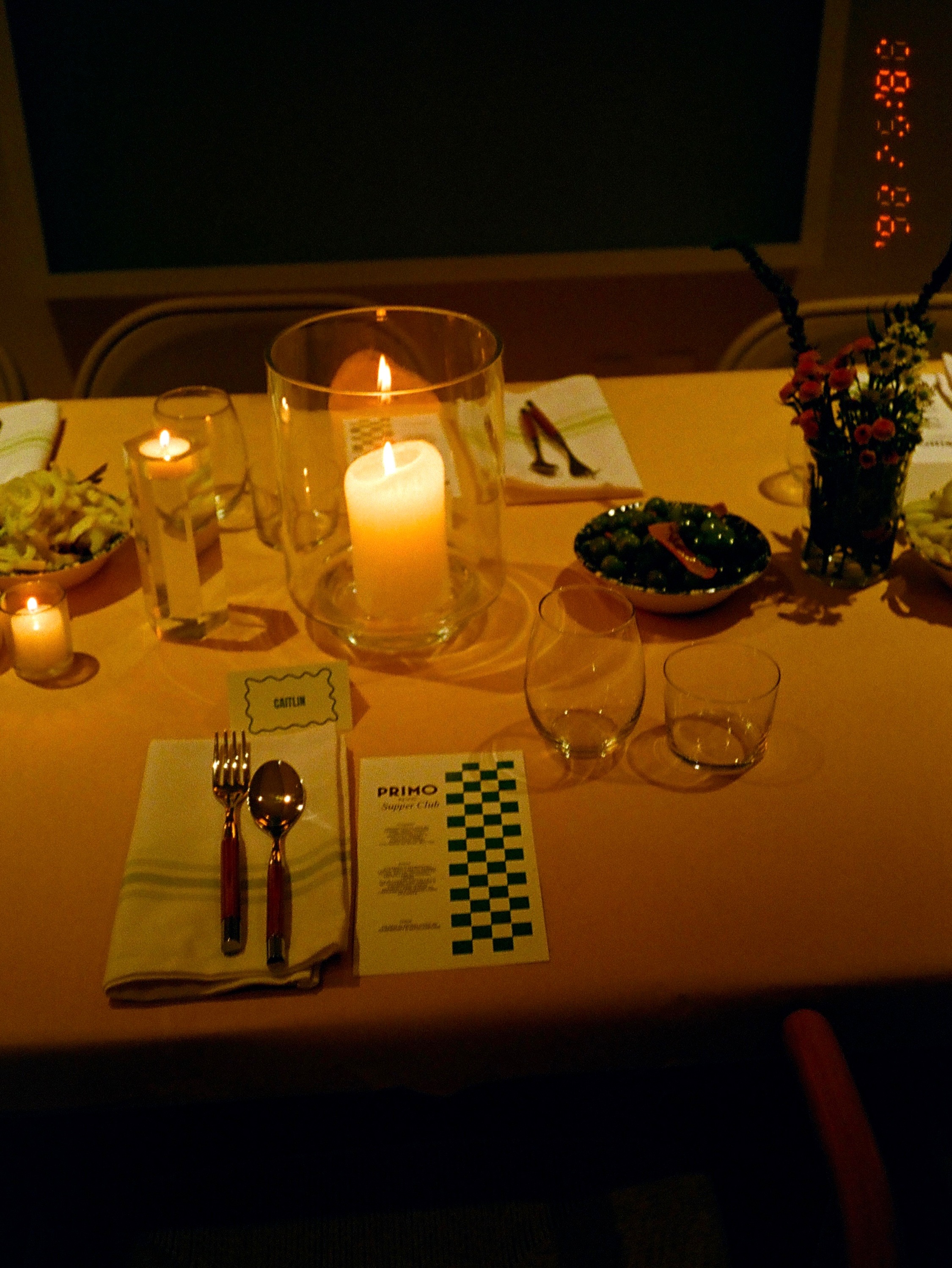 Candlelit dinner table with Primo Supper Club menu and elegant place setting